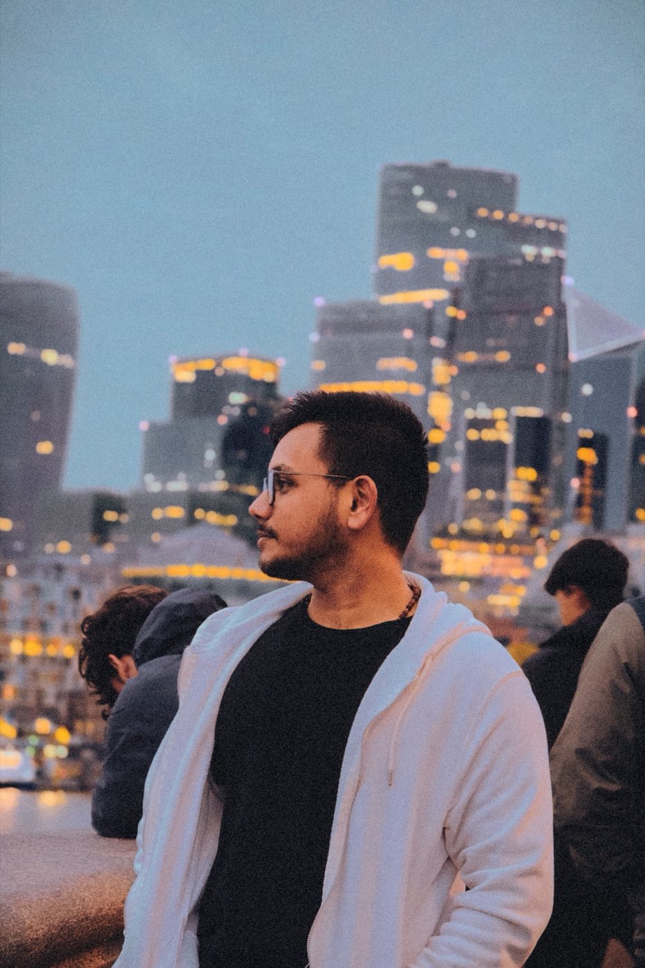 Kshitij in profile against a city skyline at dusk