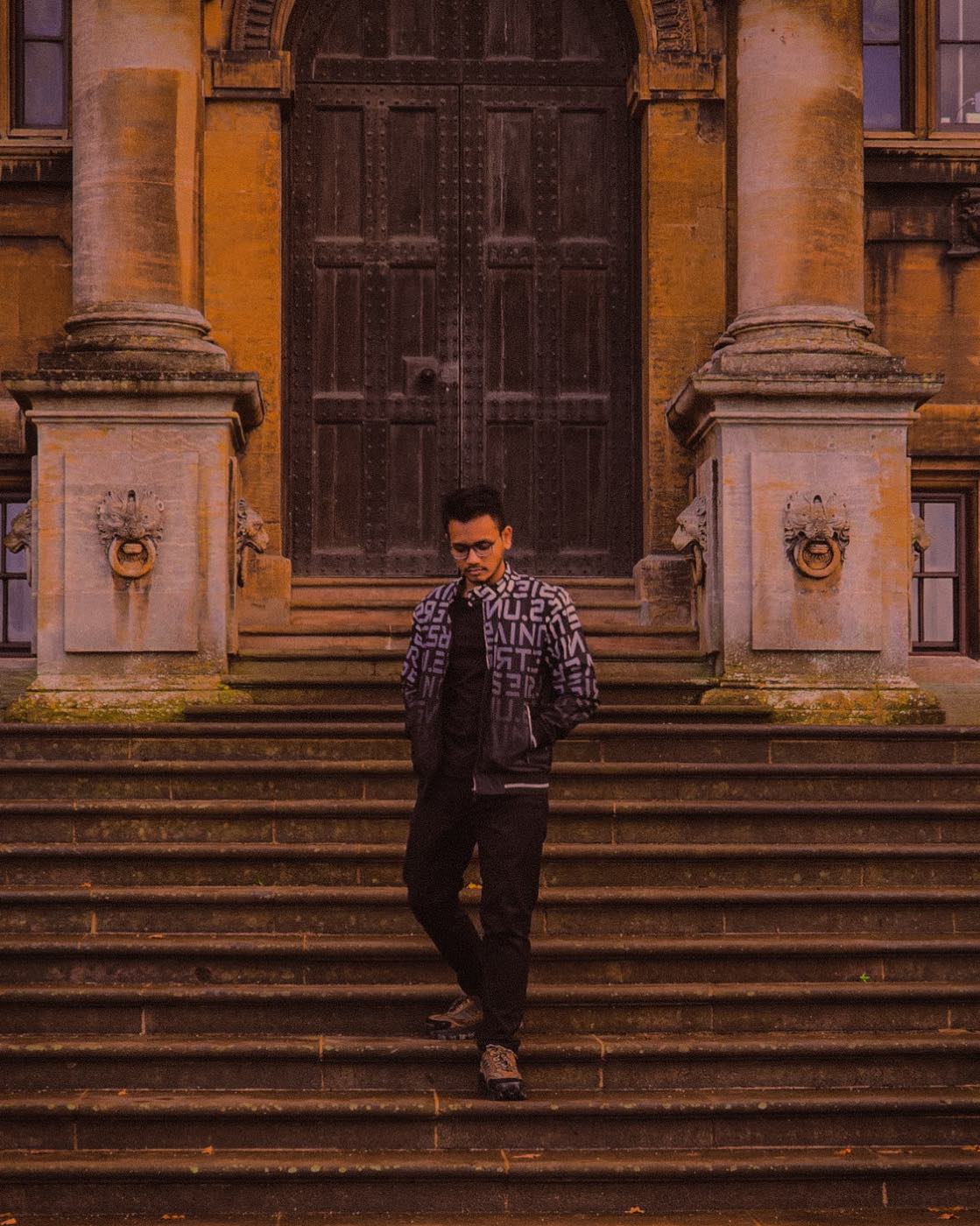 Kshitij on the steps of a stone building, beneath a tall arched door